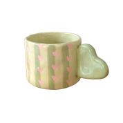 Taza de cerámica pintada a mano con asa de corazón, rayas verdes y pequeños corazones rosas.