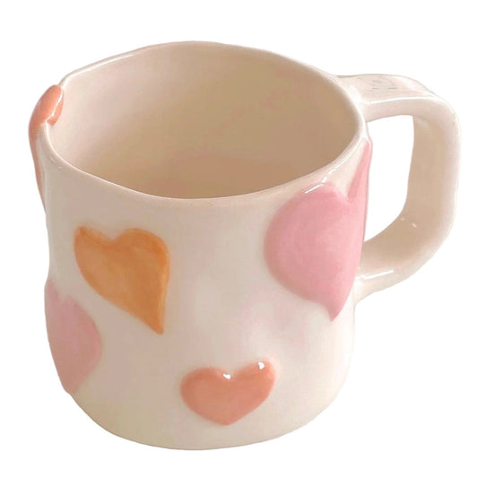 taza de cerámica con corazones en relieve pintados en tono rosa pastel
