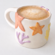 Taza de cerámica hecha a mano inspirada en el mar. Con relieves de estrellas, corales y formas orgánicas 