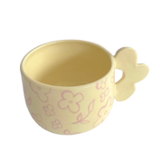 taza de ceramica de color amarillo pastel con flores pintadas y asa de flor de pipa and happy